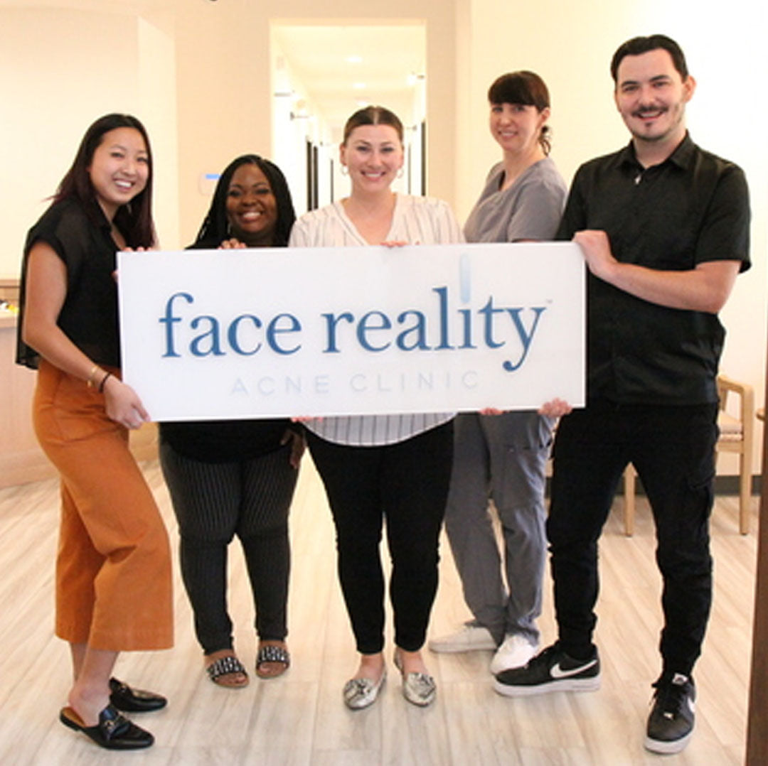 Group Photo of the Face Reality Clinic Team holding a Face Reality Clinic Sign